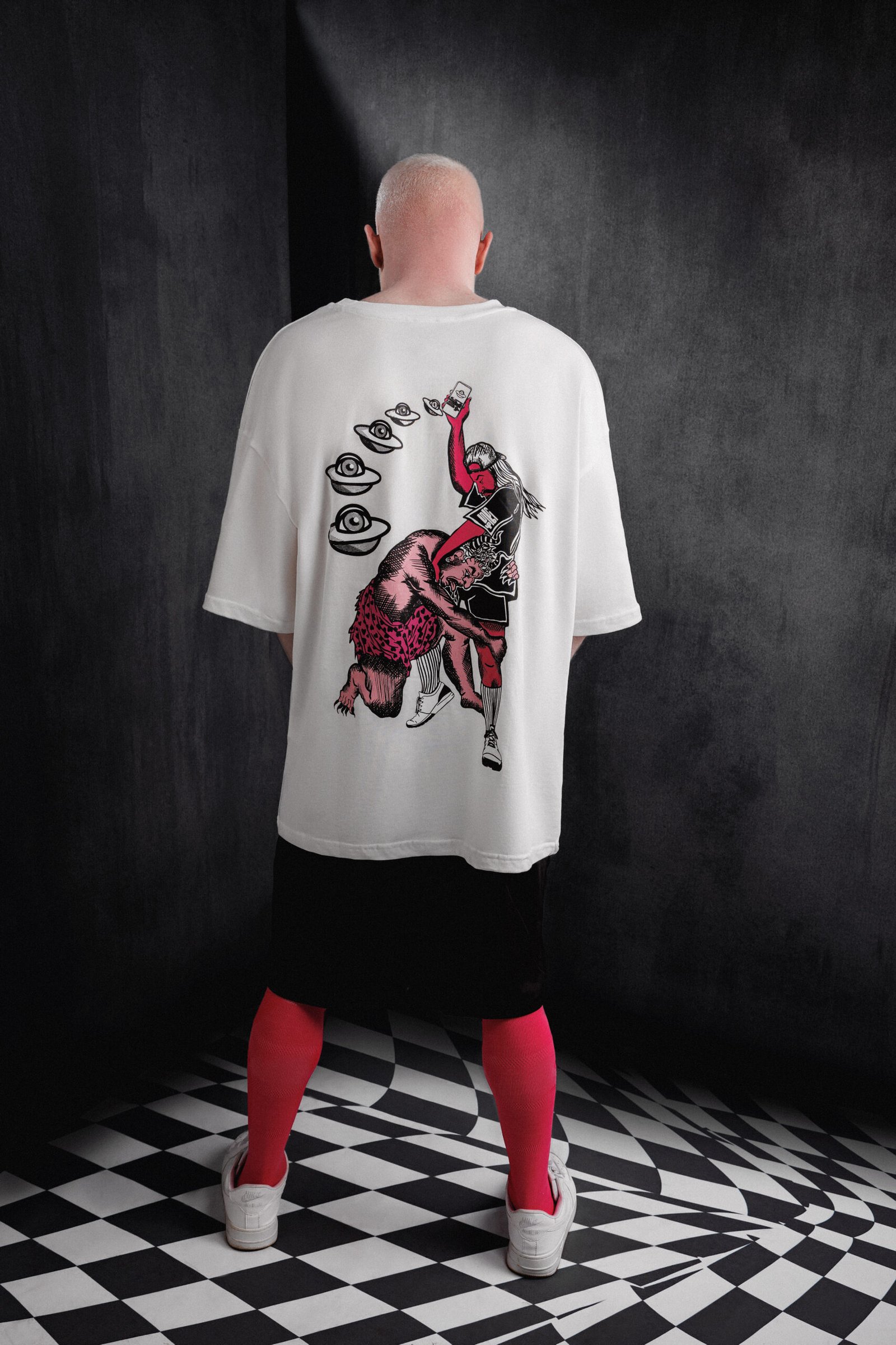 Back view of white Makouk t-shirt with pink dancing figures and UFOs. Designed by Mohamad Ali Makouk for Makouk Studios.Makouk Let Go Tee