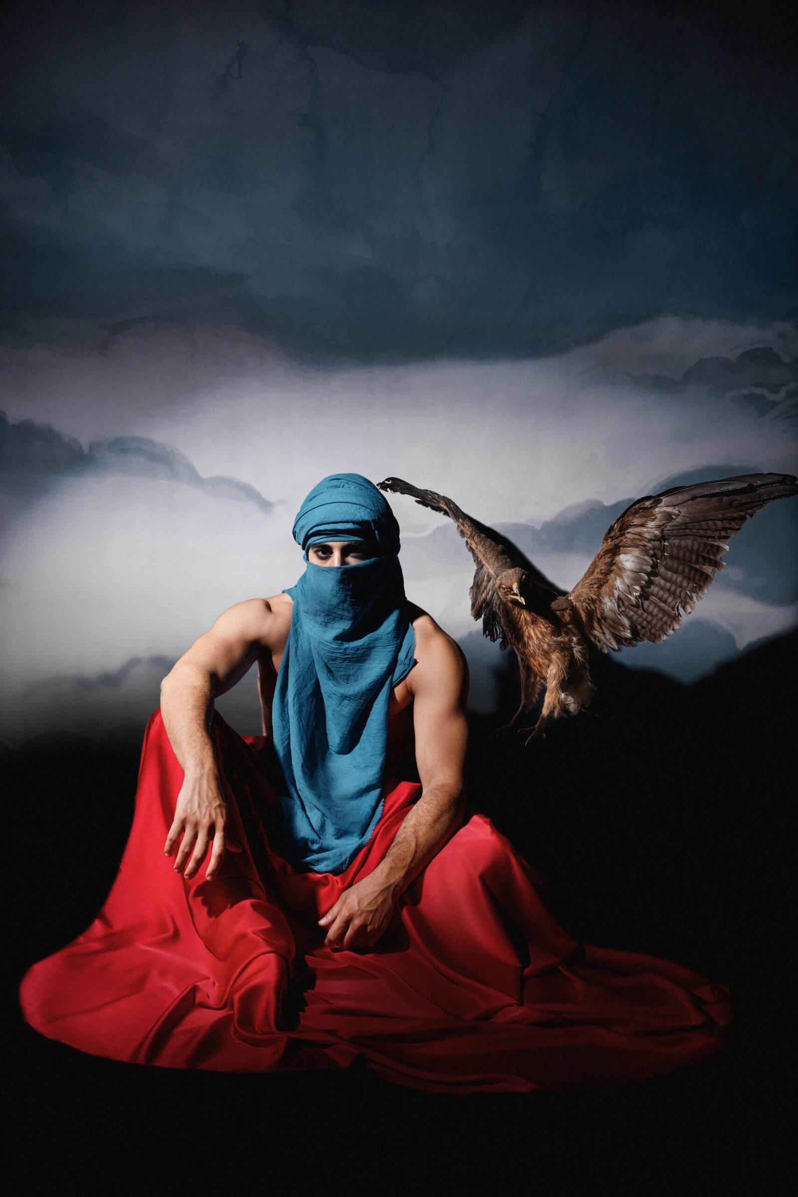 Masked model in blue veil and red drape with falcon flying beside. Designed by Mohamad Ali Makouk for Makouk Studios.