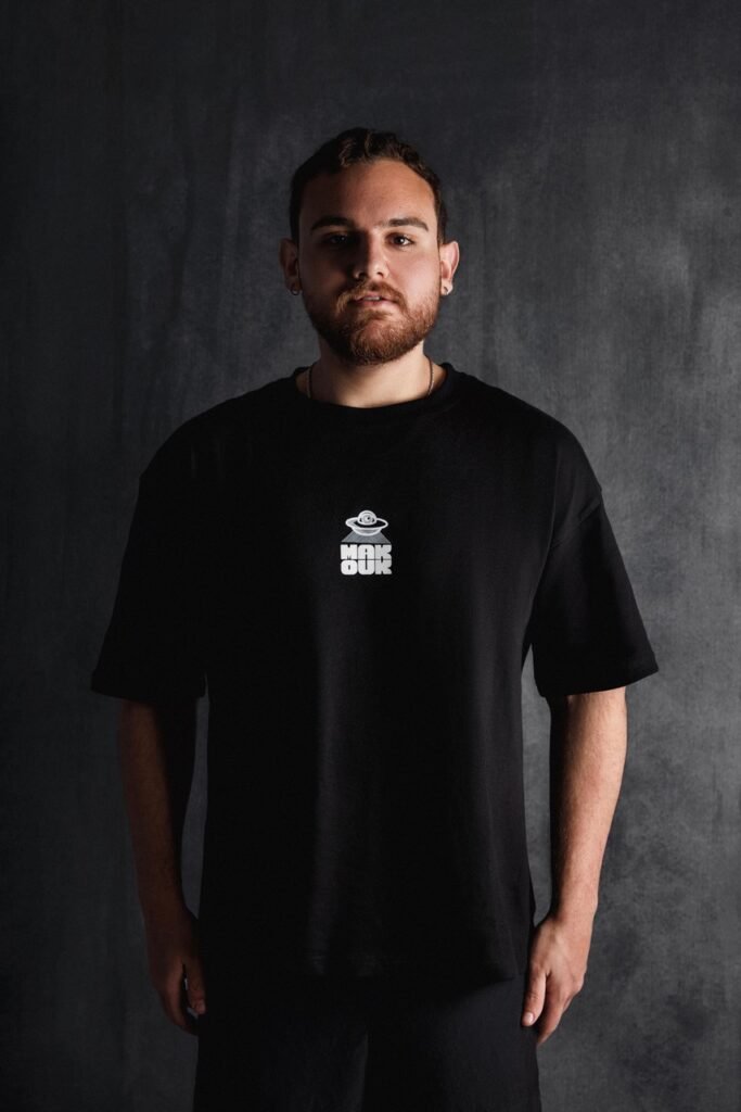 Karim Makouk, cofounder of Makouk Studios, wearing a black oversized t-shirt featuring the UFO logo.